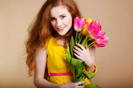 Beautiful redheared girl with bouquet of tulipsの写真素材