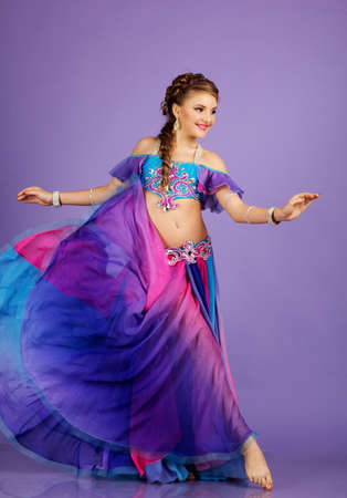Beautiful belly dancer wearing a purple costumeの写真素材
