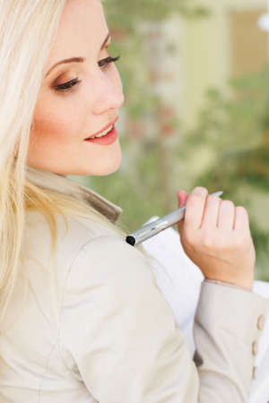 Young beautiful manager girl is holding pen and booksの写真素材