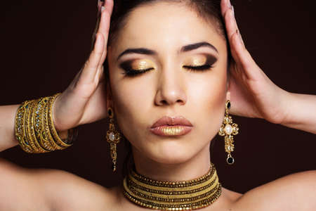 Fashion girl with golden makeup is wearing bijouterie. Fashion photo. Beauty and style