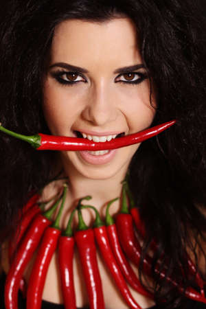 Portrait of sexy brunette girl with bead of red cayennes isolated on blackの写真素材