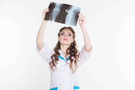 Young beautiful girl intern looking at the x-ray picture of knee isolated on whiteの写真素材