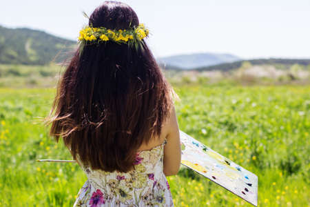 Young female artist is holding palette an floral landscape, summer timeの写真素材