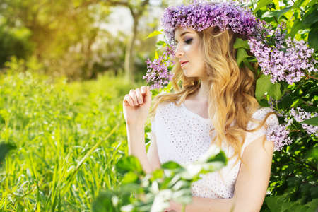 Portrait of beautiful blue-eyed teenager girl with wreath from lilac flowersの写真素材