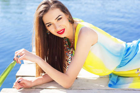 Beautiful woman is sitting near a blue lakeの写真素材