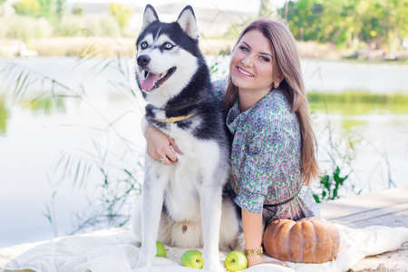 A girl and her dog husky walking in a park near lake in autumnの写真素材