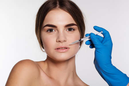 Cosmetic injection of hyaluronic acid to correct woman's lips. Isolated on white backgroundの写真素材