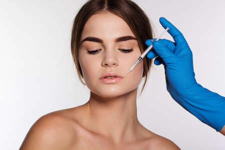 Cosmetic injection of hyaluronic acid to correct woman's lips. Isolated on white backgroundの写真素材