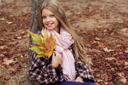 Autumn portrait of cute child girl is wearing warm coatの写真素材
