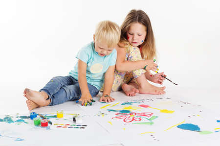 Two happy boy and girl are having fun and drawing pictures by aquarelle paintsの写真素材