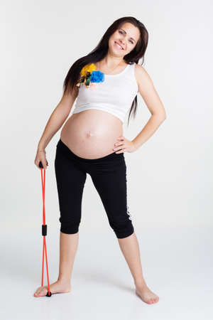 Pregnant woman doing stratching exercises with resistance bands tube isolated on white in studio