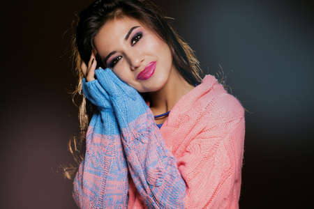Fashion photo of young magnificent woman in colorful cardigan and jewelry. Posing in studioの写真素材