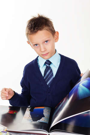 Cute little boy is looking at pictures in a book, isolated over white backgroundの写真素材