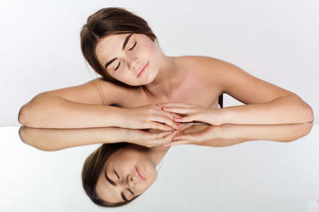 Portrait of pretty young teen girl with perfect nude makeup is near mirror with reflectionの写真素材