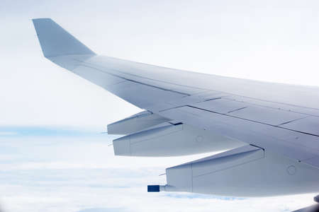 View of wing of an airplane flying above the clouds, morning timeの写真素材