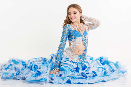 Beautiful young girl is wearing blue suit oriental dance in motion isolated on white backgroundの写真素材