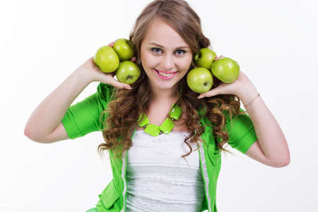 Pretty young and healthy girl is holding green apples isolated on white in studioの写真素材