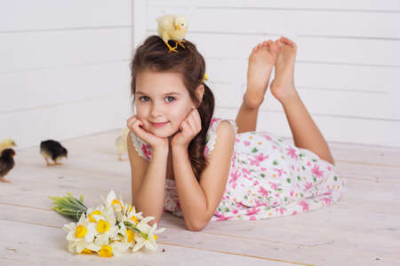Happy pretty child girl with yellow small chicks in her headの写真素材