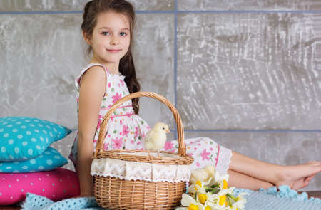 Happy pretty child girl with basket full of small chicksの写真素材