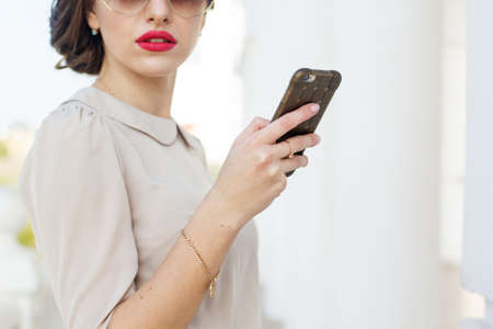 Beautiful business woman is holding phone in handsの写真素材