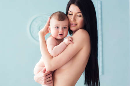 Mother is holding her naked baby over blue backgroundの写真素材