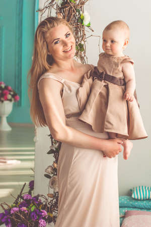 Portrait of young mother is holding little daughter are wearing fashion dressesの写真素材