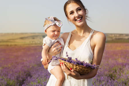 Happy couple mom is having fun with her baby girl in purple lavender field, summer timeの写真素材