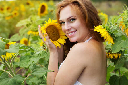 Redheared happy smiling girl is holding sunflower in handsの写真素材