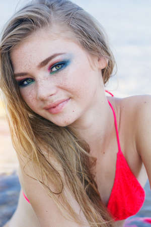 Beauty smiling teenager girl with freckles over her face is wearing bikini near seaの写真素材