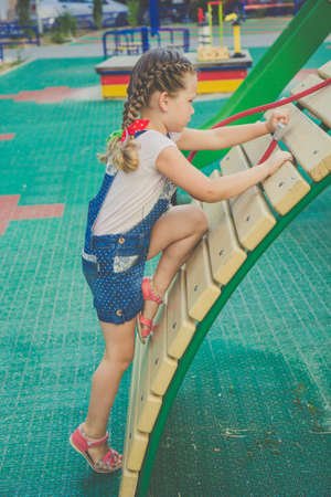 Pretty smiling cute girl is clumbing on a playgroundの写真素材