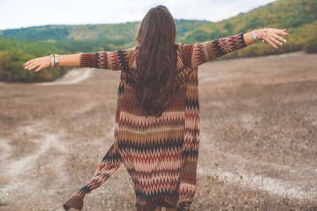 Back view of young pretty woman is wearing clothes in bohemian style on the natureの写真素材