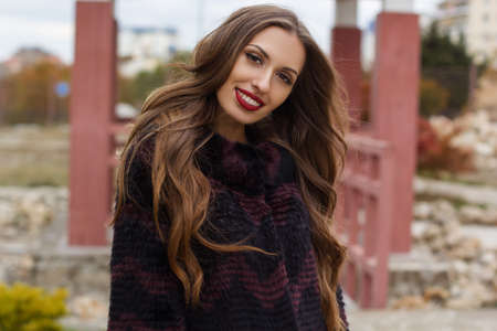 Beautiful gorgeous smiling woman is wearing luxury dark fur coat walking in parkの写真素材
