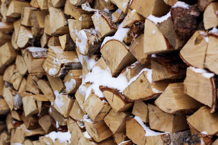 Chopped firewood logs in a pile with snowの写真素材