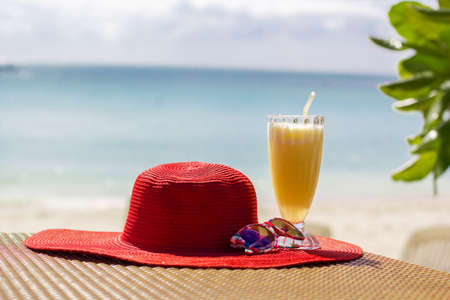 Orange fresh juice, hat and sunglasses over seaの写真素材