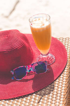 Orange fresh juice, hat and sunglasses over seaの写真素材