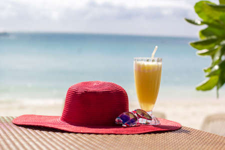 Orange fresh juice, hat and sunglasses over seaの写真素材