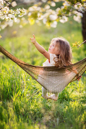 Pretty child girl is having fun in hammock outdoorsの写真素材