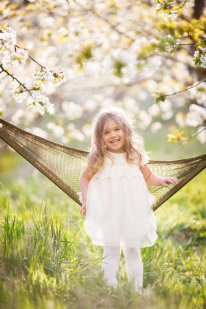 Pretty child girl in hammock in blossom gardenの写真素材