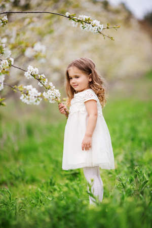 Pretty child girl in blossom spring gardenの写真素材
