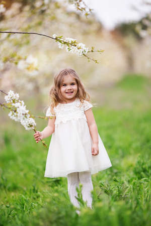 Pretty child girl in blossom spring gardenの写真素材