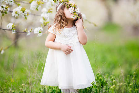 Pretty child girl is smelling flowers in gardenの写真素材