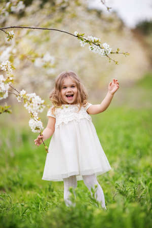 Pretty child girl in blossom spring gardenの写真素材