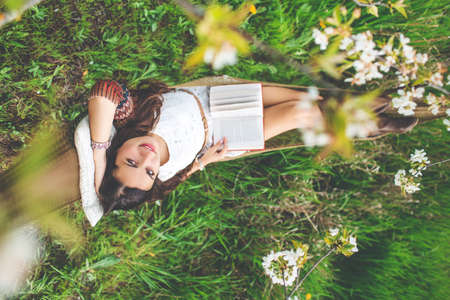 Woman is reading book in hammock outdoorsの写真素材
