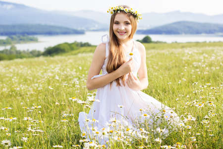 Cute child girl is lying at  green camomile fieldの写真素材