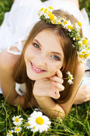 Cute child girl is lying at  green camomile fieldの写真素材