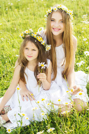 Cute sisters girls is playing at  green camomile fieldの写真素材