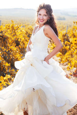 Smiling happy bride wearing nice white dress is walking in a vineyard wedding time.の写真素材