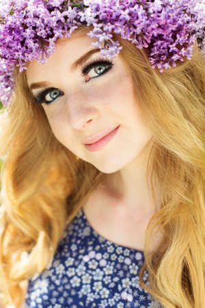 Portrait of beautiful blue-eyed teenager girl with wreath from lilac flowersの写真素材