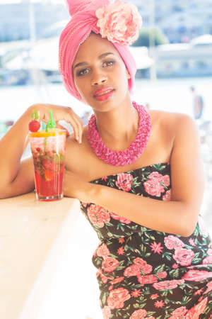 Young south african zulu woman is sitting near bar and drinking mojito, summer timeの写真素材