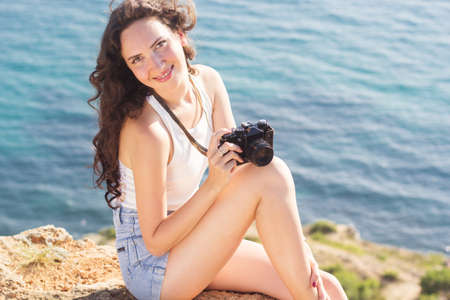 Portrait of tourist happy smiling girl making photos of the nature and sea views by old camera...